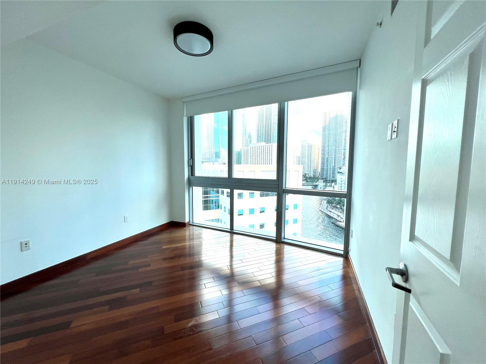 350 South Miami Avenue, Unit 1502 Miami, FL 33130 - Photo 9 of 30 a view of an empty room with wooden floor and a window