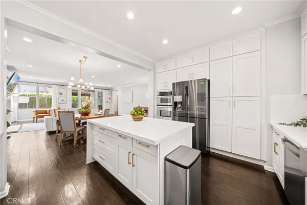 a kitchen with granite countertop a stove a sink dishwasher and white cabinets with wooden floor