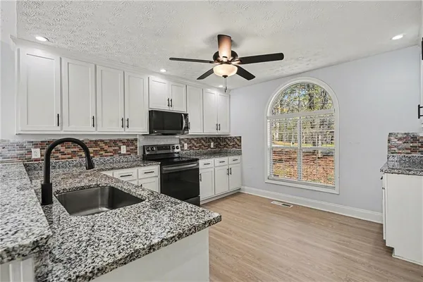 a kitchen with a stove a sink a microwave and cabinets