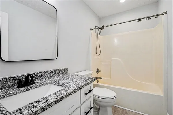 a bathroom with a granite countertop sink toilet and shower