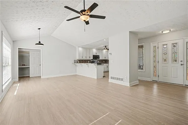 a view of a big room with wooden floor and a kitchen