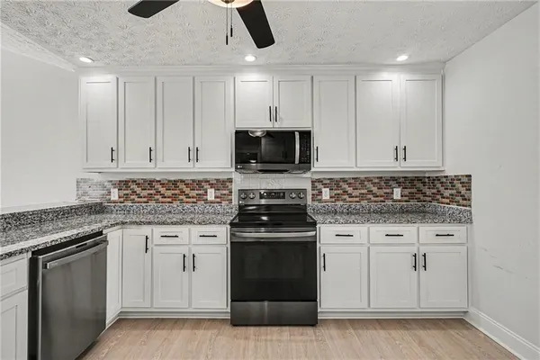 a kitchen with granite countertop white cabinets and stainless steel appliances