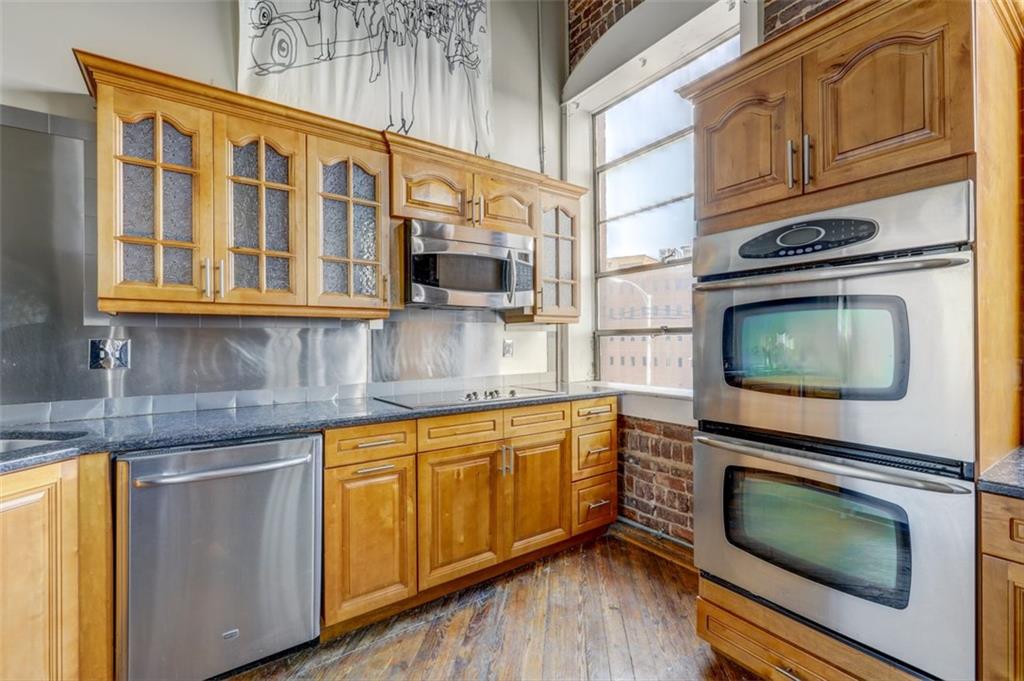 161 Mangum Street Southwest, Unit 302 Atlanta, GA 30313 - Photo 9 of 33 a kitchen with stainless steel appliances granite countertop wooden cabinets and a stove top oven