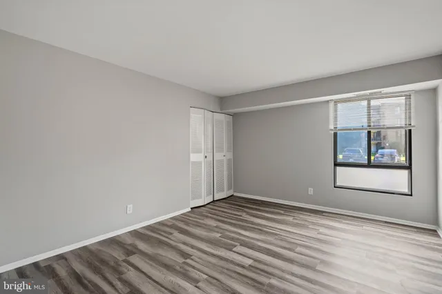 a view of an empty room with window and wooden floor