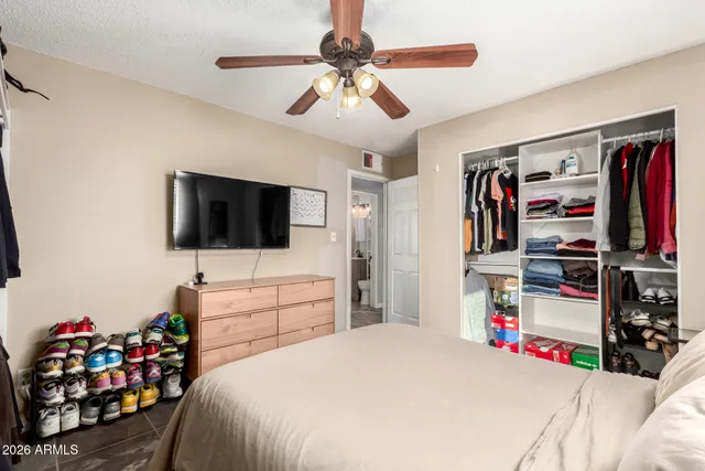 a bedroom with a bed a flat screen tv and windows