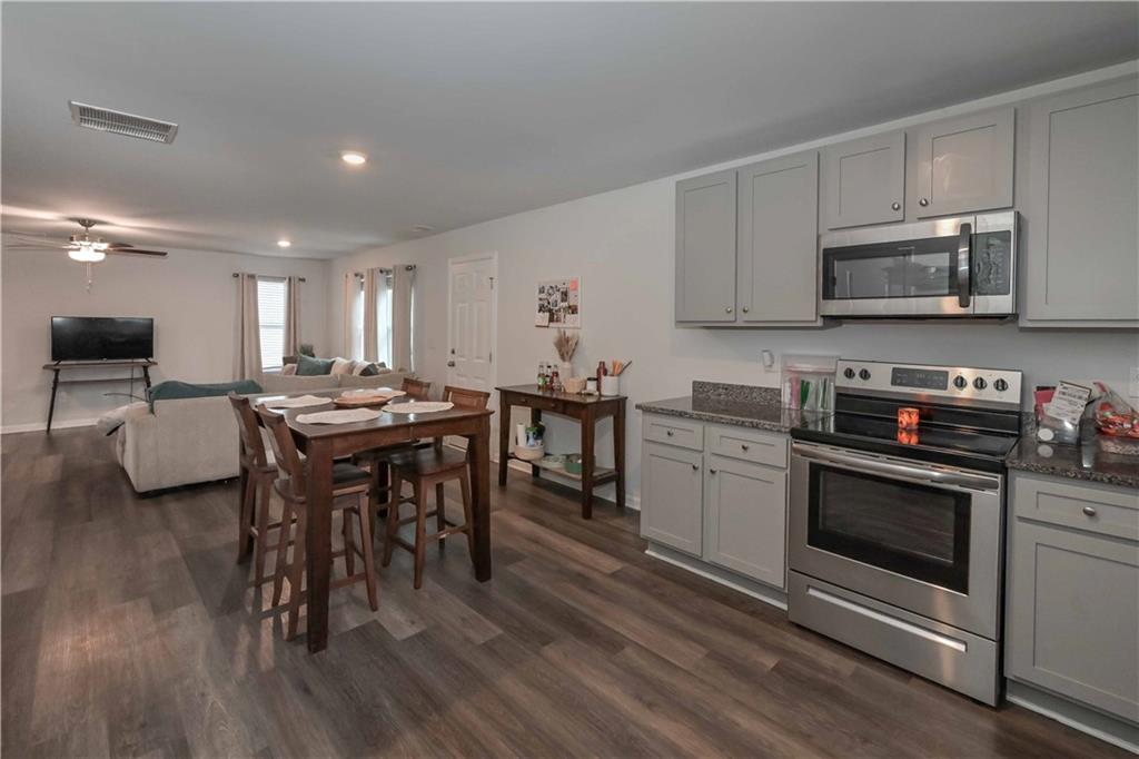 294 Muskogee Drive Dallas, GA 30132 - Photo 18 of 32 a kitchen with stainless steel appliances kitchen island granite countertop a stove a sink a microwave and wooden floors