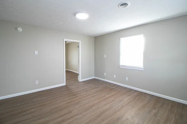 an empty room with wooden floor and windows