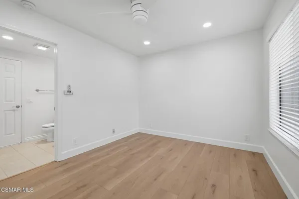 an empty room with wooden floor ceiling fan and windows
