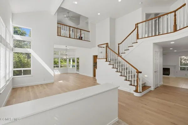 a view of an entryway with wooden floor leading to a furnished livingroom and windows