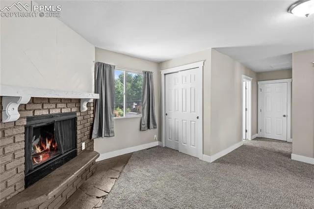 a view of an empty room with a fireplace and window