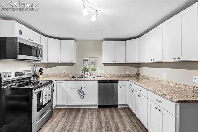 a kitchen with stainless steel appliances granite countertop a stove top oven a sink dishwasher and a refrigerator
