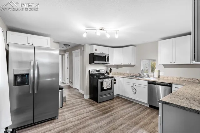 a kitchen with granite countertop a refrigerator a sink a stove top oven and cabinetry