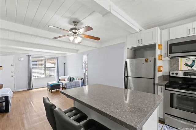 a kitchen with stainless steel appliances granite countertop a sink a refrigerator a stove a dining table and chairs with wooden floor