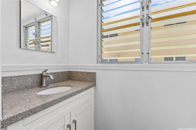 a bathroom with a granite countertop sink and a window