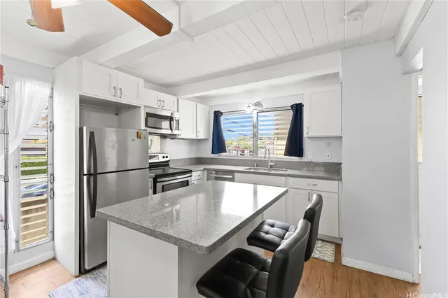 a kitchen with kitchen island a counter top space cabinets stainless steel appliances and a window