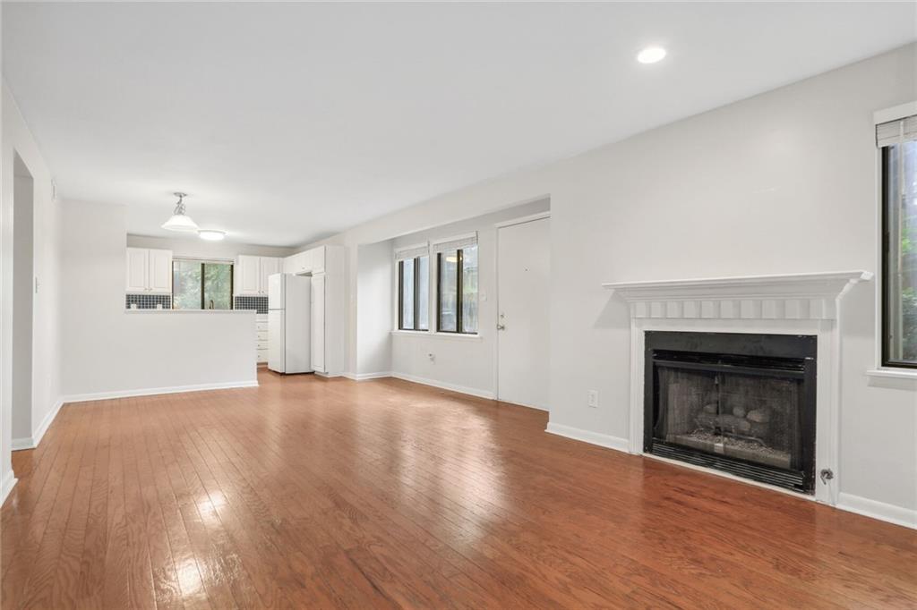 a view of an empty room with wooden floor fireplace and a window