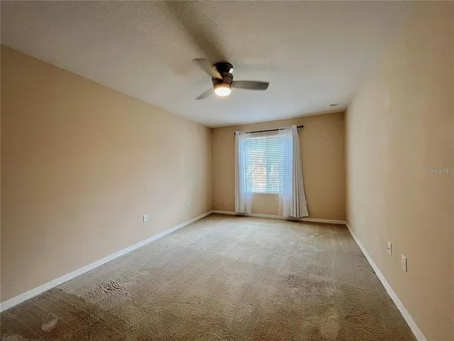 an empty room with a ceiling fan and a window