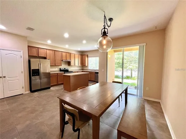 a kitchen with stainless steel appliances granite countertop a refrigerator a oven a stove a sink dishwasher and a dining table with wooden floor