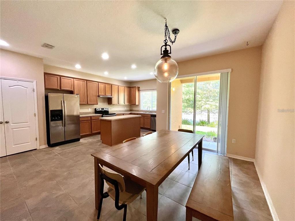 5552 Rutherford Place Oviedo, FL 32765 - Photo 6 of 20 a kitchen with stainless steel appliances granite countertop a refrigerator a oven a stove a sink dishwasher and a dining table with wooden floor