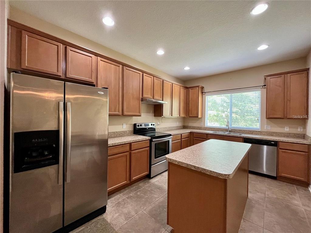 5552 Rutherford Place Oviedo, FL 32765 - Photo 7 of 20 a kitchen with stainless steel appliances granite countertop a refrigerator a sink dishwasher a stove top oven a refrigerator with grey cabinets and wooden floor