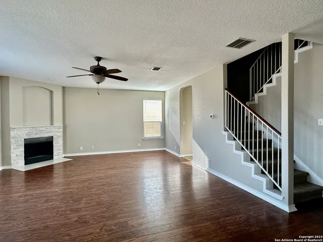 a view of an empty room with wooden floor fireplace and a window