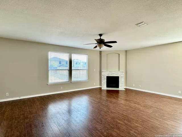 a view of a livingroom with a fireplace wooden floor and a window