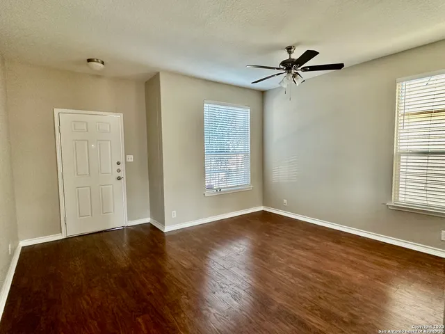 a view of an empty room with wooden floor and a window