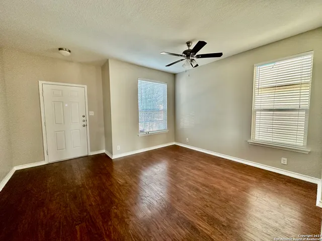 a view of an empty room with a window and wooden floor