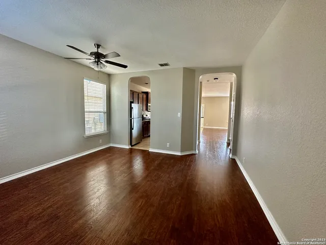 a view of empty room with wooden floor and fan
