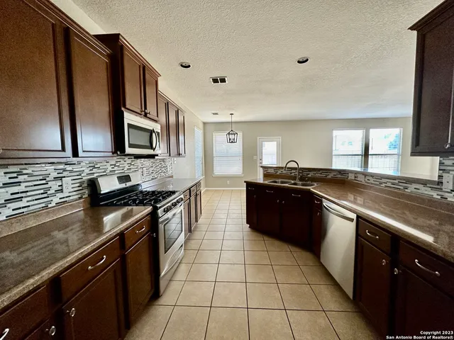 a large kitchen with stainless steel appliances granite countertop a stove a sink and a microwave