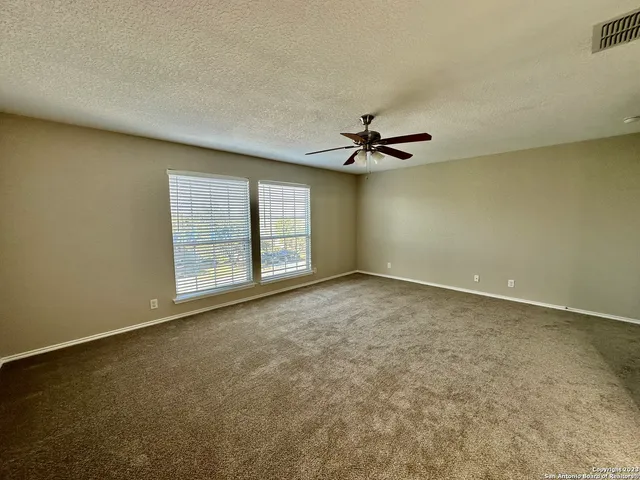 an empty room with windows and ceiling fan view