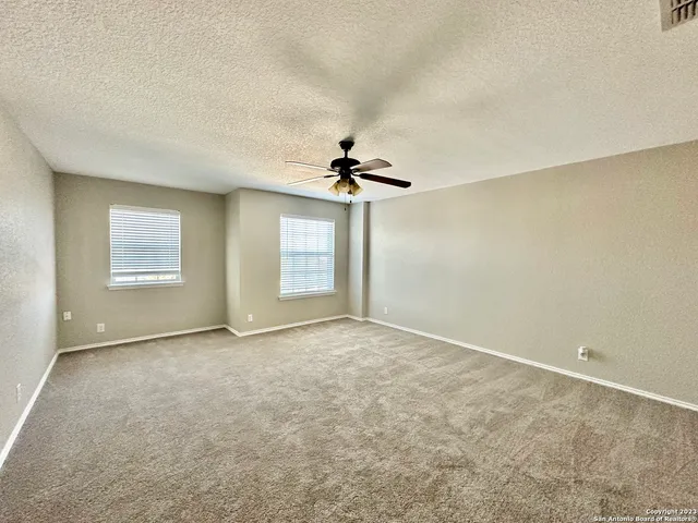 an empty room with windows and ceiling fan view