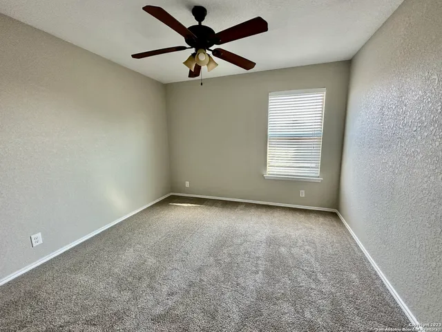 an empty room with a window and a fan