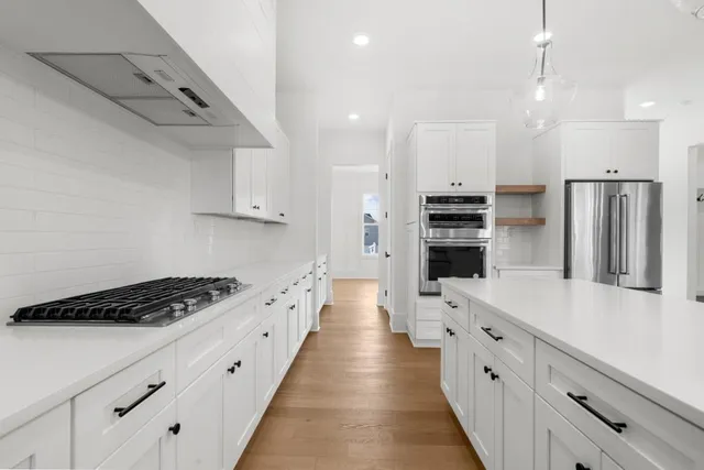 a large kitchen with kitchen island a stove a sink a center island and wooden floor