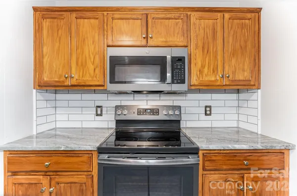 a kitchen with granite countertop wood cabinets stainless steel appliances and a sink