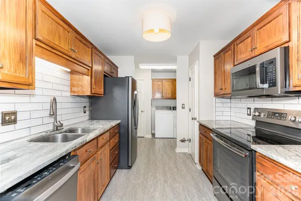 a kitchen with stainless steel appliances granite countertop a sink stove microwave refrigerator and wooden cabinets