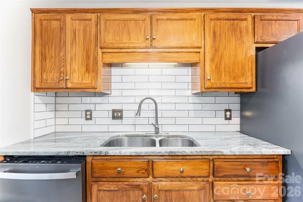 a kitchen with granite countertop a sink a stove and cabinets