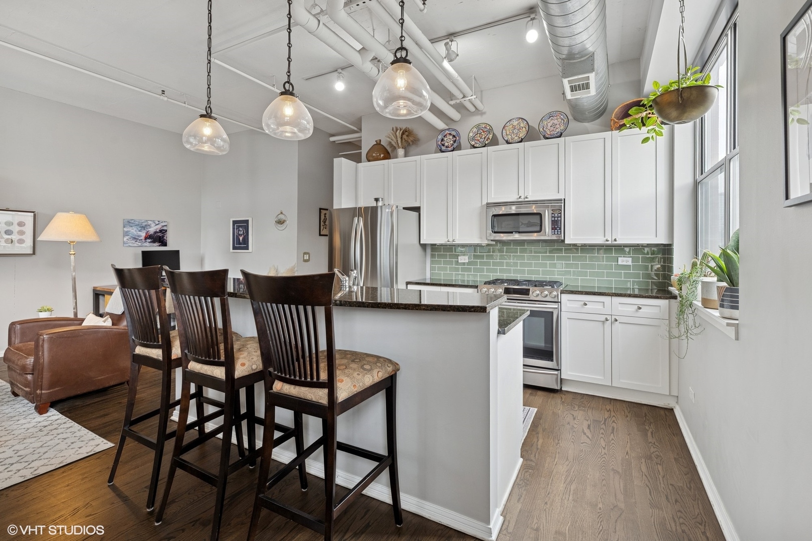 950 West Monroe Street, Unit 410 Chicago, IL 60607 - Photo 7 of 23 a kitchen with stainless steel appliances kitchen island granite countertop a dining table chairs refrigerator and microwave