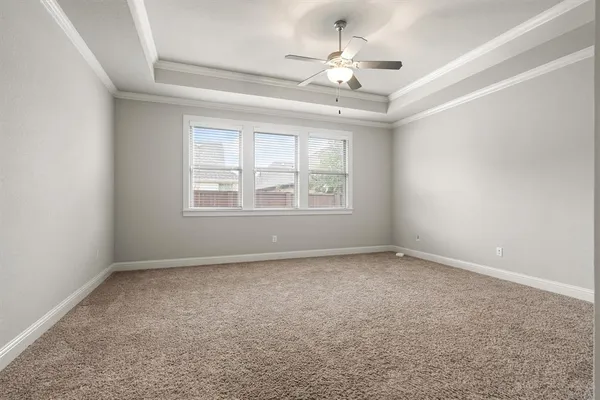 an empty room with a chandelier fan and windows