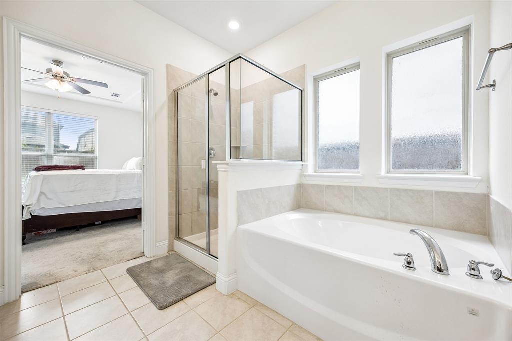 11732 Wulstone Road Fort Worth, TX 76052 - Photo 11 of 34 Spacious bathroom featuring a built-in bathtub with polished chrome fixtures, a clear glass shower enclosure, and light-toned tile flooring