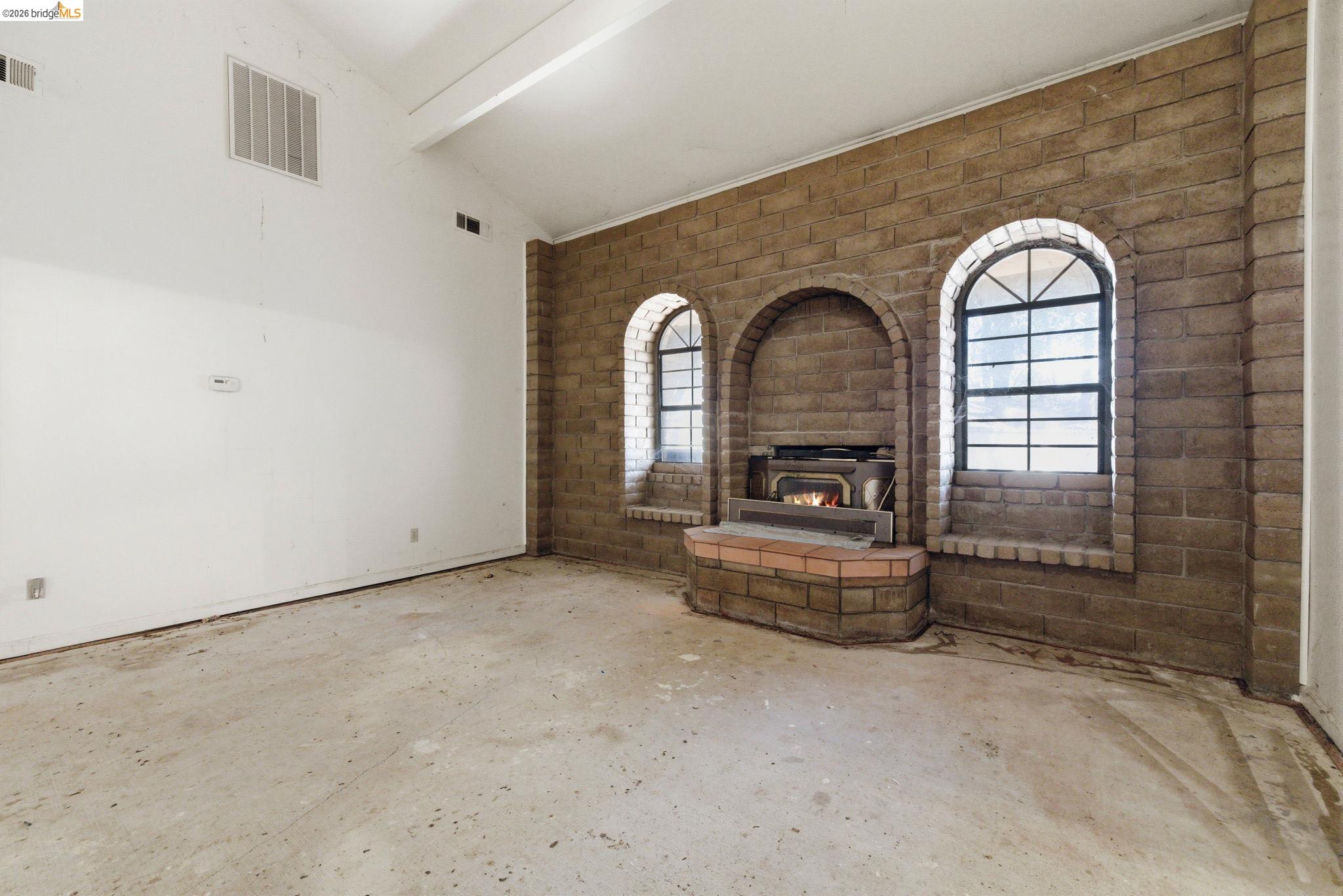 23608 Porcina Way Columbia, CA 95310 - Photo 43 of 51 Unfurnished living room with concrete floors, vaulted ceiling with beams, and brick wall