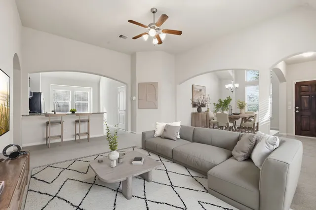 a living room with furniture kitchen view and a chandelier