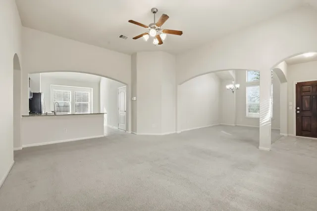 an empty room with chandelier fan and windows
