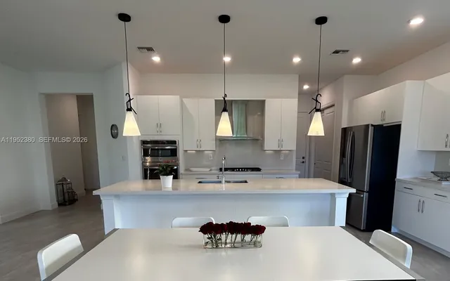 a kitchen with kitchen island a refrigerator a sink and a stove