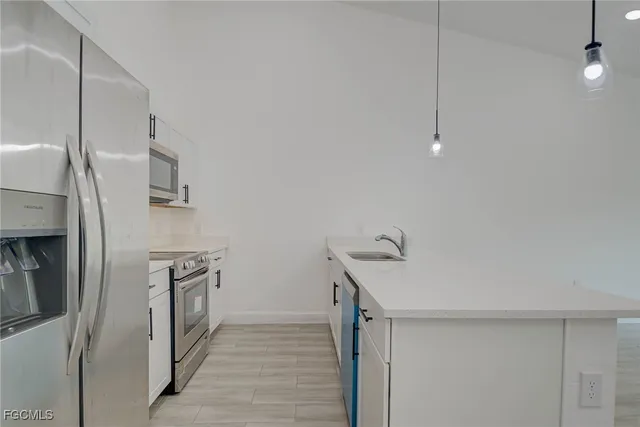 a kitchen with stainless steel appliances granite countertop a sink a stove and a refrigerator with white countertops