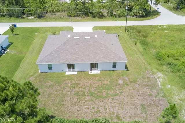 an aerial view of residential houses with outdoor space and trees