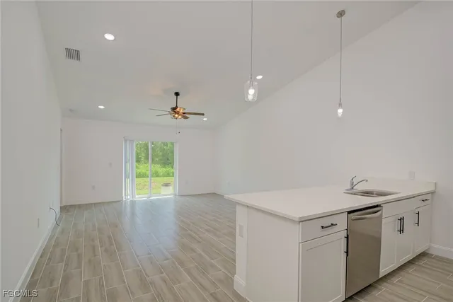 a view of a kitchen with a sink and dishwasher with wooden floor