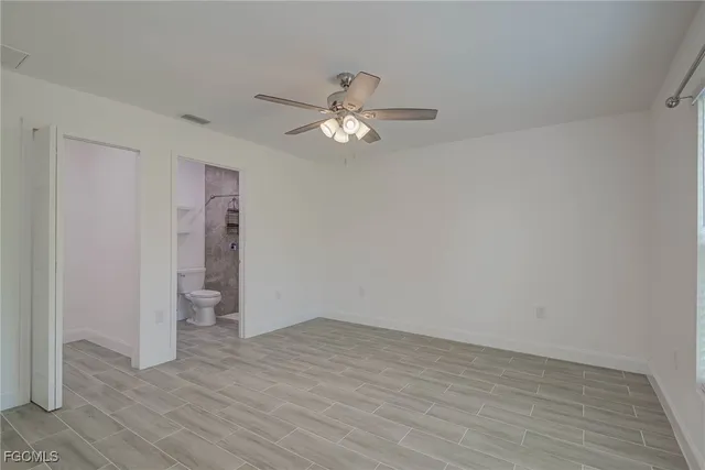an empty room with wooden floor chandelier fan and windows