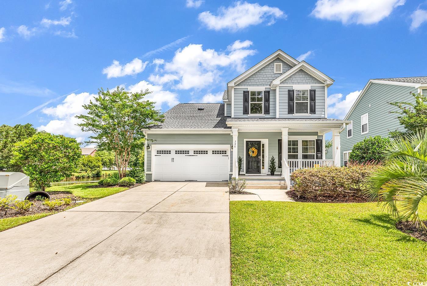 View of front facade with covered porch, a garage, concrete driveway, and a front lawn