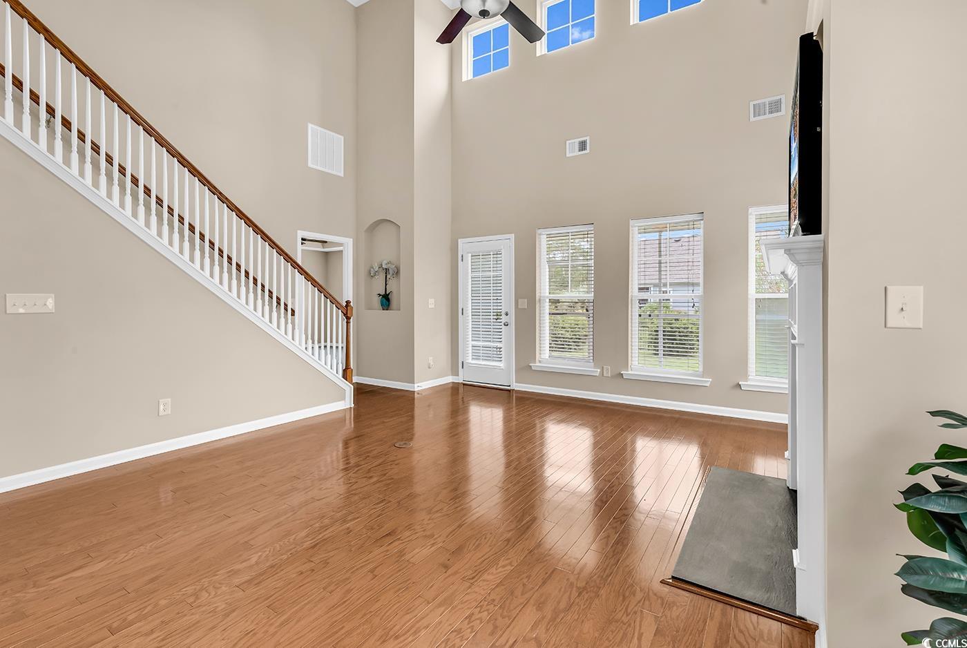 126 Dreamland Drive Murrells Inlet, SC 29576 - Photo 10 of 40 Unfurnished living room featuring a ceiling fan, wood finished floors, baseboards, a towering ceiling, and stairway